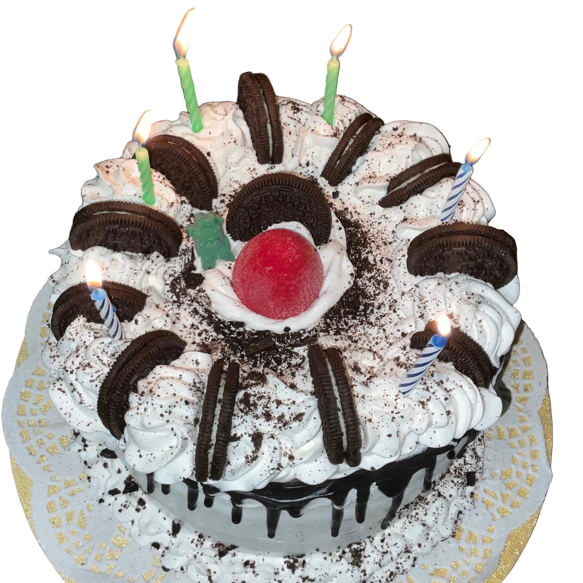 Birthday cake with white frosting, Oreo cookies, and lit candles on a granite countertop.